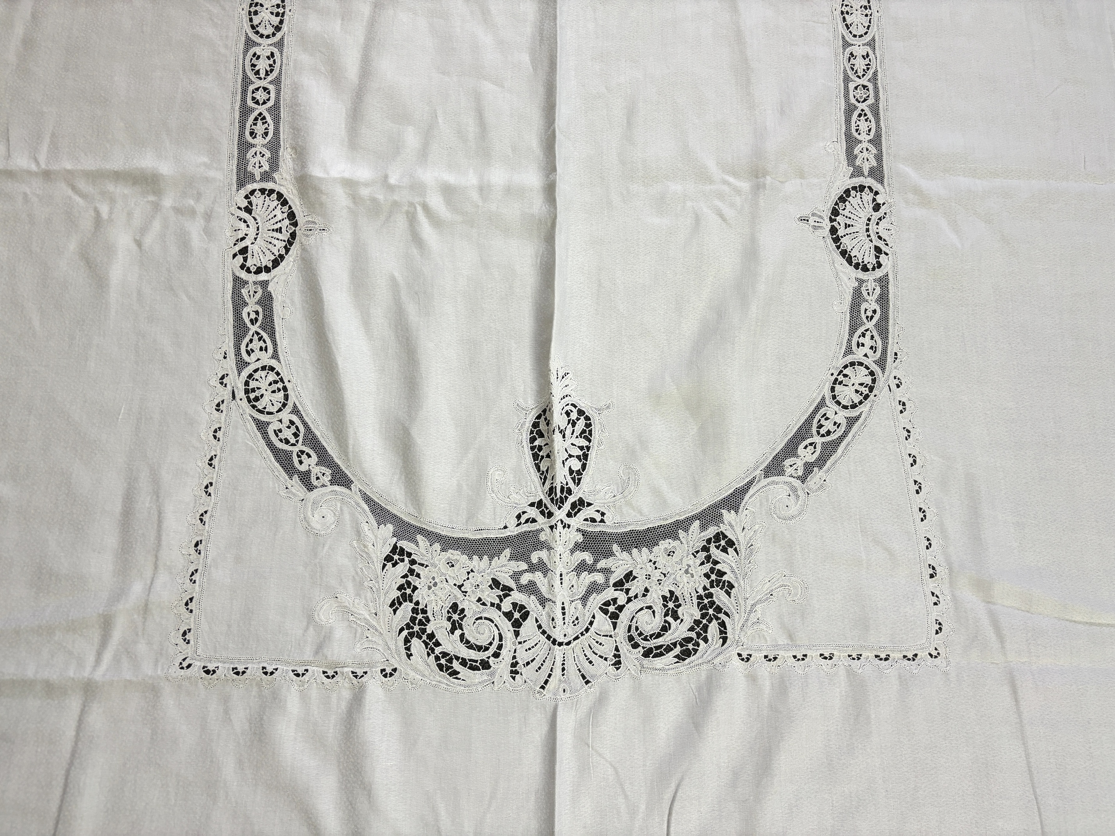 An Edwardian damask banqueting cloth 354cm long x 232 wide, worked with a central needle lace inserted cartouche, together with a smaller linen table cloth, 264cm long x 226cm wide, bordered with bobbin lace edges and si